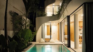Un área moderna junto a la piscina con una piscina cristalina, una tumbona y una escalera que lleva a un nivel superior.