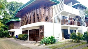 Uma casa moderna de dois andares com garagem, cercada por vegetação e um caminho de acesso pavimentado.