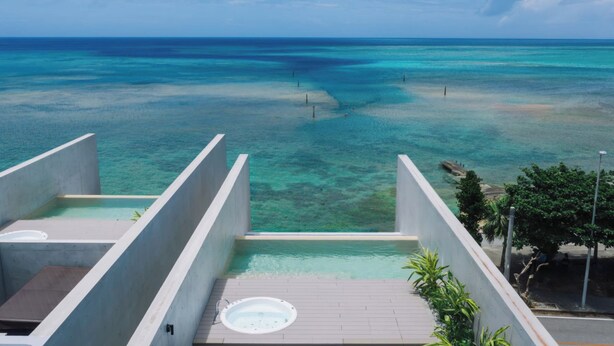A rooftop pool with a hot tub, overlooking a turquoise sea. - CELEVI Yomitan (Yomitan)