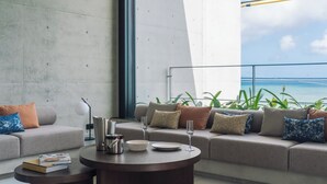 A modern living room with a sofa, a coffee table, and a view of the ocean. - CELEVI Yomitan (Yomitan)