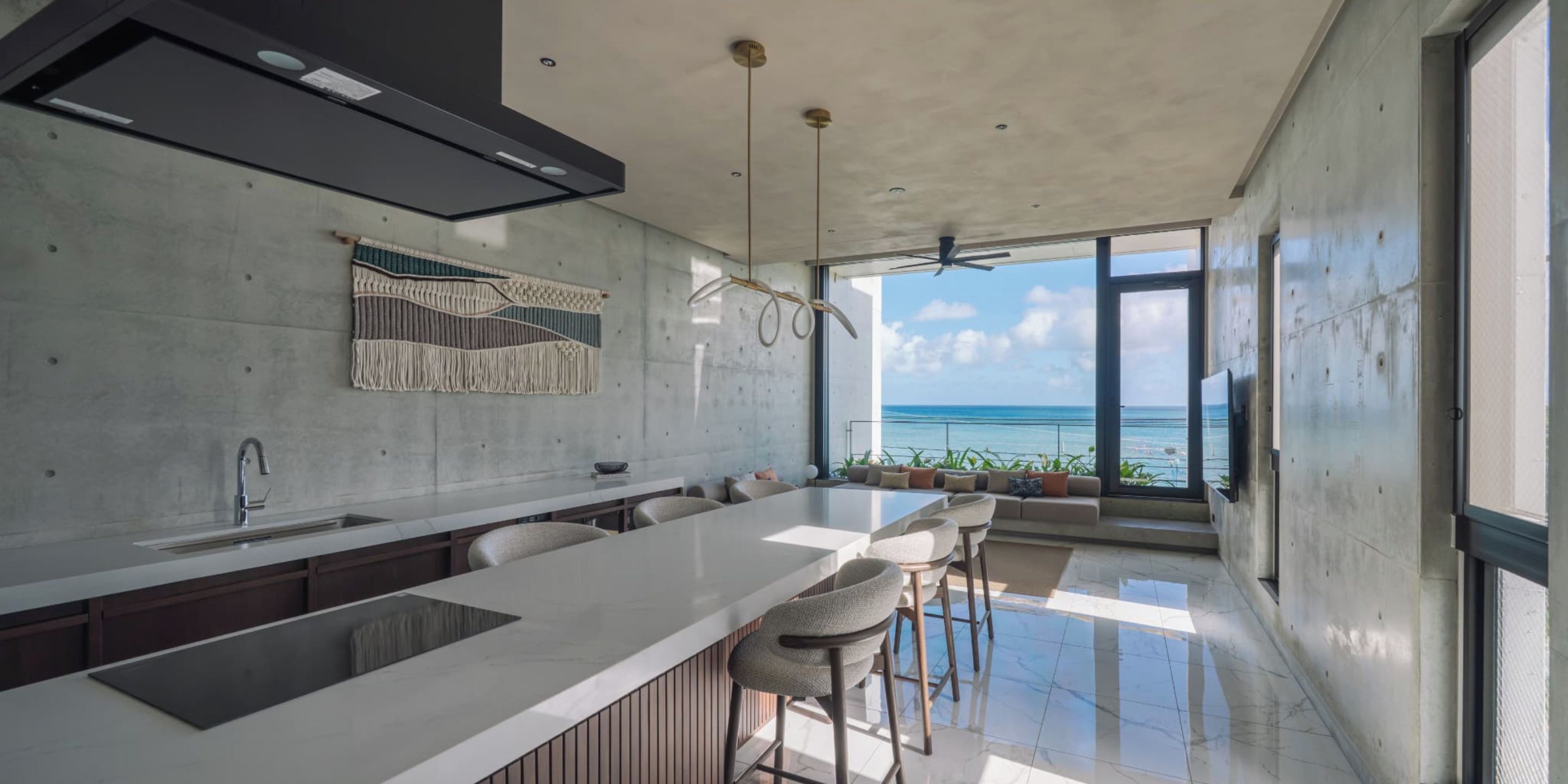 A modern kitchen with a large island, a built-in sink, and a view of the ocean.