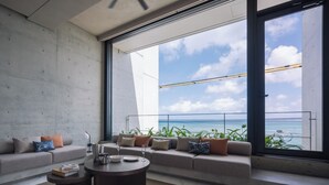 A modern living room with a large window overlooking the ocean, a sofa set, and a coffee table. - CELEVI Yomitan (Yomitan)