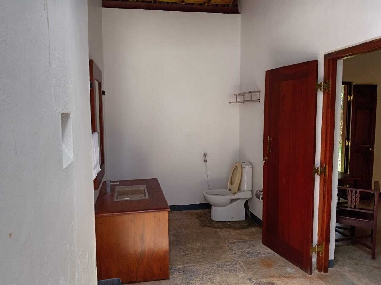 A small, compact bathroom with a toilet, a wooden cabinet, and a shower area.