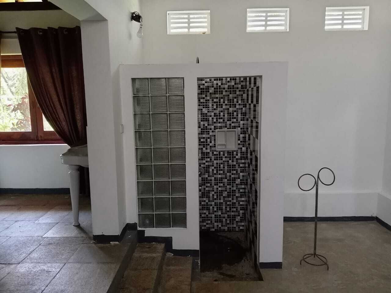 A room with a white door, a tiled wall, and a metal stand.