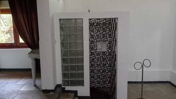 A room with a white door, a tiled wall, and a metal stand.