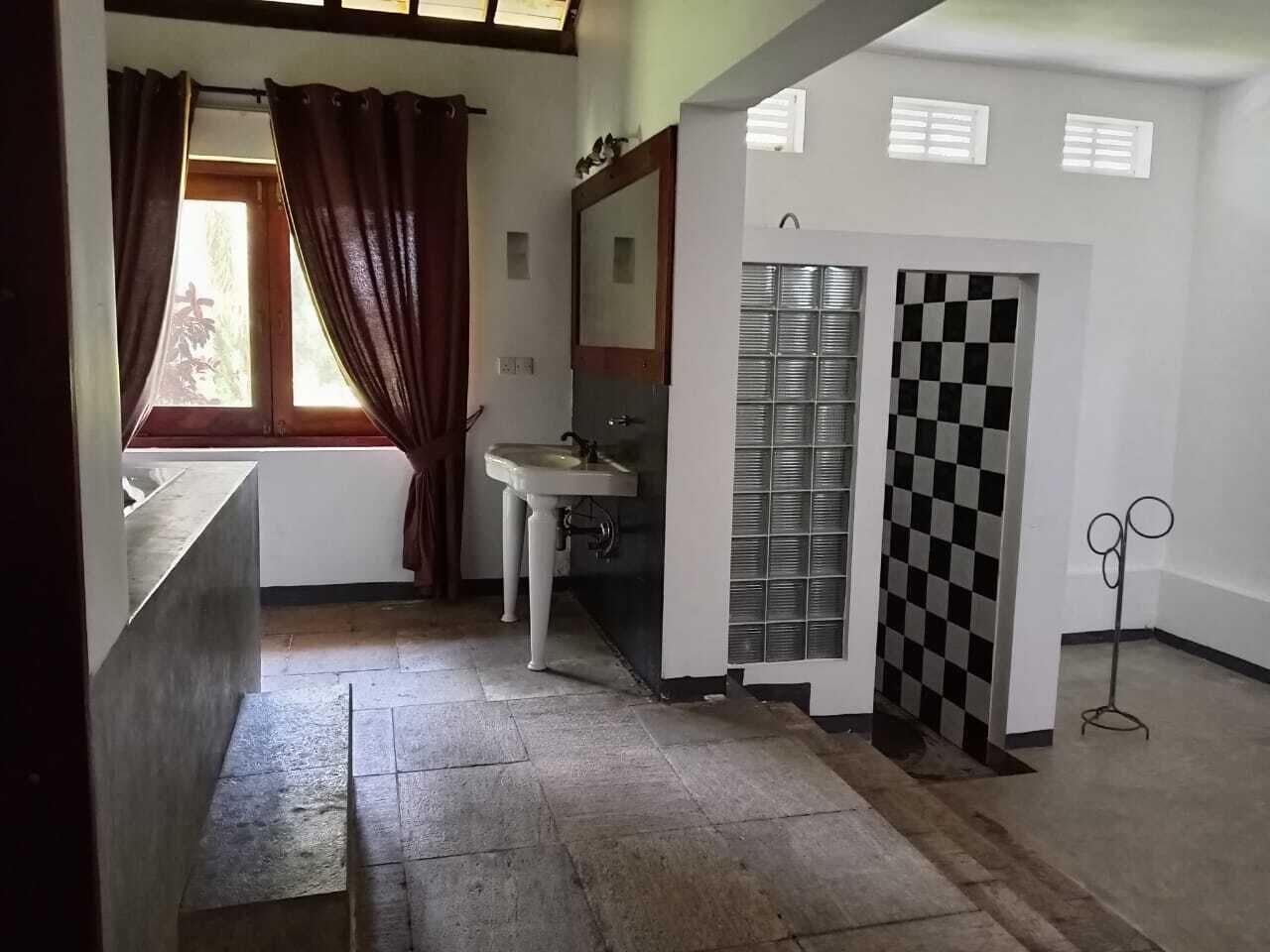 Een kamer met een raam, een wastafel, een spiegel, een geruit behang en een metalen standaard.