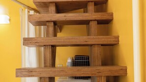 A wooden staircase with a white railing, leading to a room with a white door and a small table with a bottle and a container on it. - House Hotel nakano TNA (Tokyo)