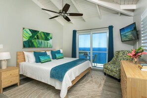 A bedroom with a bed, a desk, a chair, a TV, a ceiling fan, a window with curtains, and a painting.