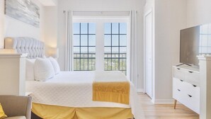 A bedroom with a bed, a TV, and a balcony view. - Stylish 1BR Suite w/ Kitchen & Balcony Near Universal & Epic Universe (Orlando)