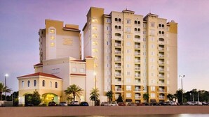A multi-story hotel with a prominent sign, a pool, and a parking area. - Stylish 1BR Suite w/ Kitchen & Balcony Near Universal & Epic Universe (Orlando)