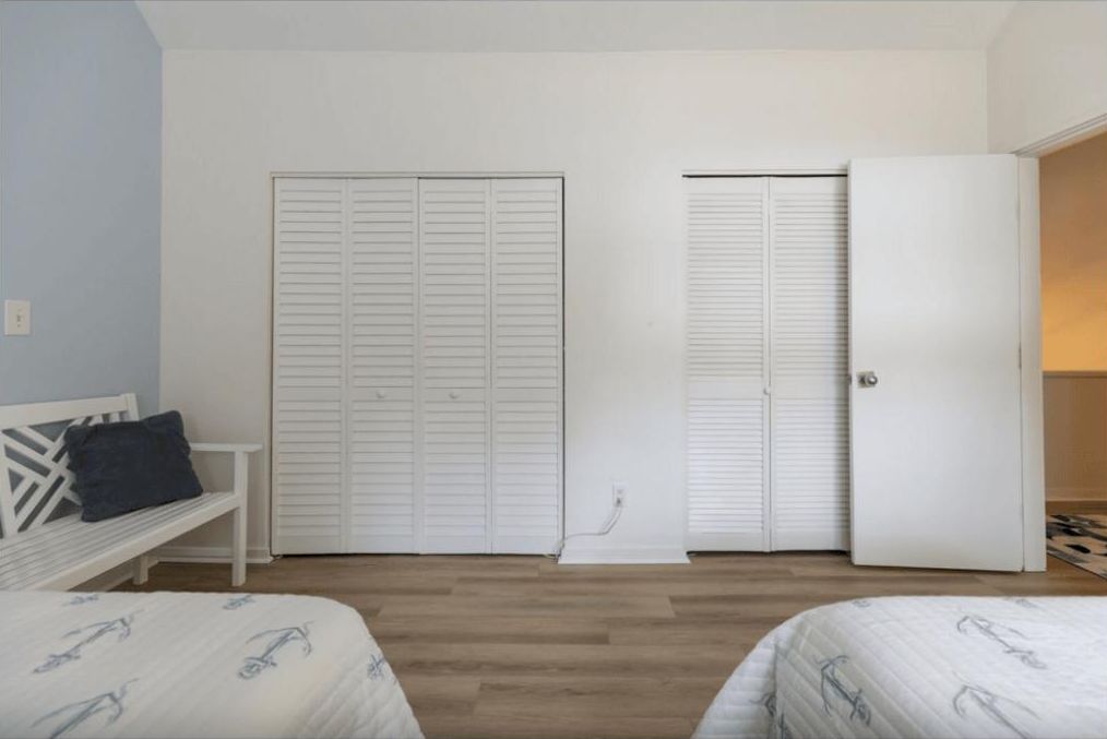 Camera da letto con due letti, un'armadio bianco e una panca.