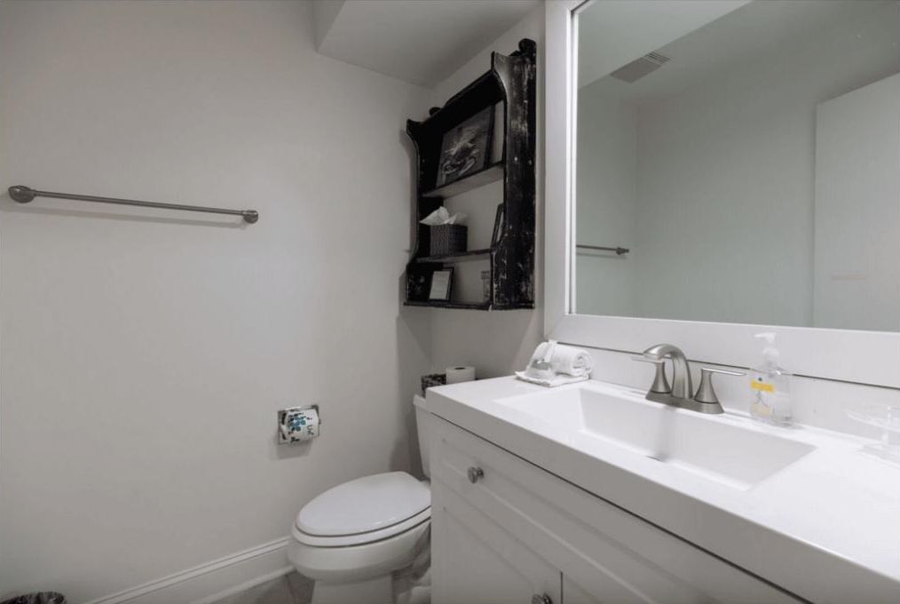 A bathroom with a white sink, a mirror, a toilet, and a towel rack.