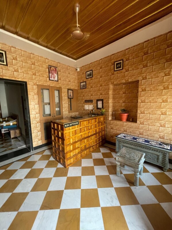 A reception area with a checkered floor, wooden reception desk, and a small bench.