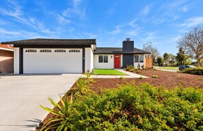 A modern two-story house with a garage, a red door, and a well-maintained front yard with various plants. - Cozy Family Stay 3BR/2BA Home in Prime Milpitas Location (Milpitas)