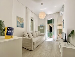 A modern living room with a sofa, a table with a book, and a painting on the wall.