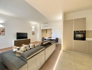 A modern living room with a sectional sofa, a flat-screen TV, and a dining area with chairs. - CasaViva - Central Wonderful Home in Santa M. (Santa Margherita Ligure)