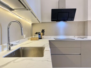A modern kitchen with a stainless steel sink, a built-in oven, and a flat-screen TV mounted above the countertop. - CasaViva - Central Wonderful Home in Santa M. (Santa Margherita Ligure)