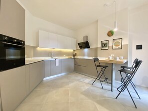 Een moderne keuken met een ingebouwde oven, een spoelbak en een eethoek met twee stoelen.