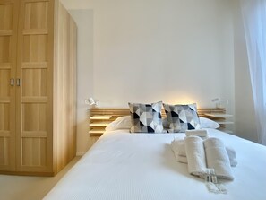 A hotel room with a large wardrobe, a bed with white bedding, geometric patterned pillows, and a bedside table with a lamp. - CasaViva - Central Wonderful Home in Santa M. (Santa Margherita Ligure)