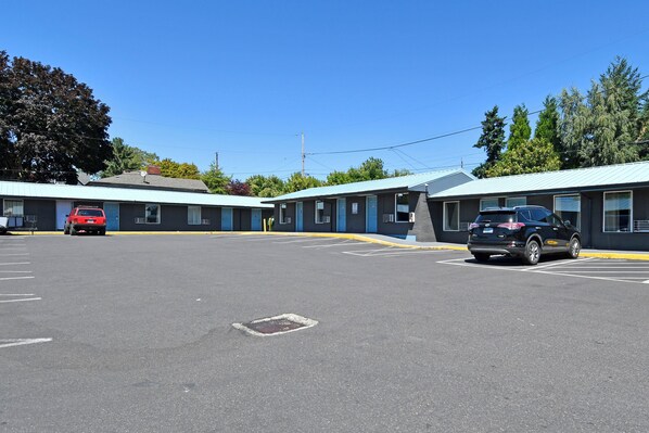 A motel with two-story buildings, a parking lot, and a red car parked in the lot.