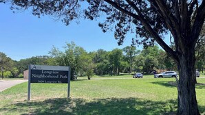 A sign for Longview Neighborhood Park with a clear view of the surrounding greenery and parked cars.