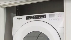 En tvättmaskin och en torktumlare från Whirlpool, placerade ovanpå varandra i ett vitt skåp.