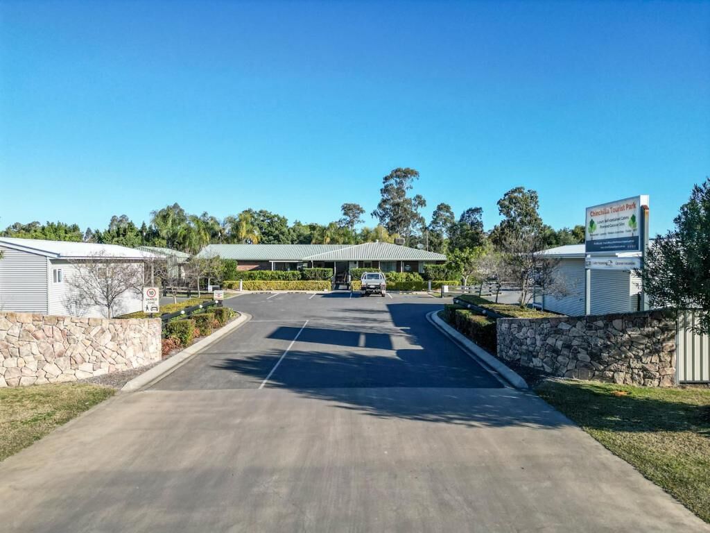 A road leading to a building with a sign for 'Chinchilla Tourist Park'.