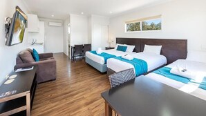 Ein modernes Hotelzimmer mit zwei Betten, einer Couch, einem Schreibtisch und einem Essbereich.