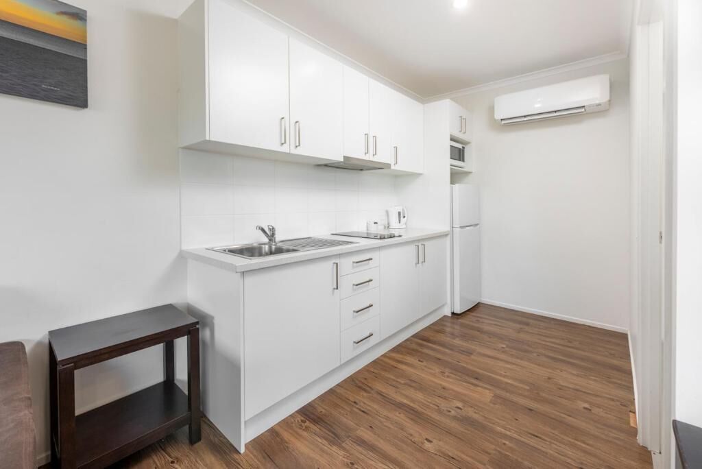 A modern kitchen with white cabinets, a built-in oven, and a microwave.