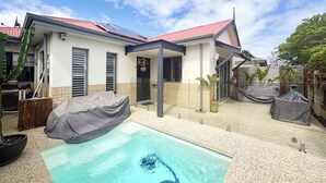 Ein modernes Haus mit Swimmingpool, überdachter Terrasse und Solaranlage auf dem Dach.