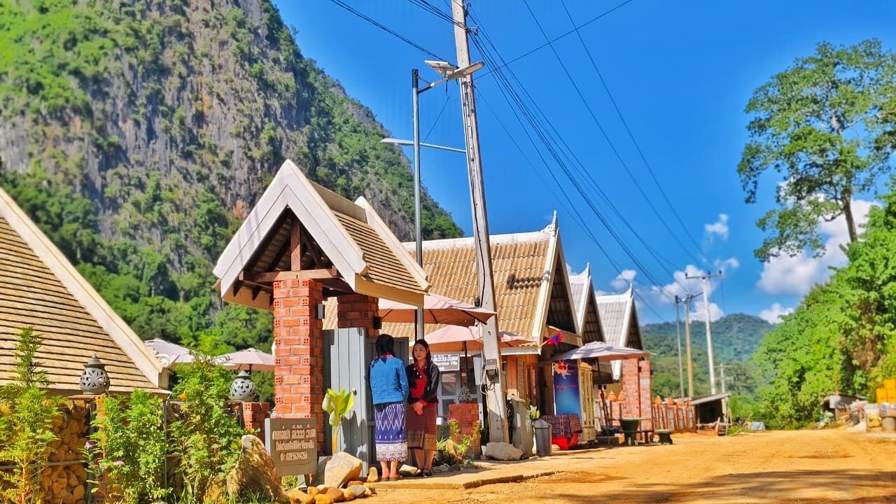 Un bâtiment traditionnel en bois, doté d’un toit en pente, d’une enseigne et d’un chemin de terre devant l’entrée.