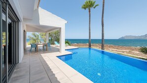 A modern outdoor pool area with a clear view of the sea, a covered seating area, and a pathway leading to the pool. - ES TAMARELLS (S'ESTANYOL) - Villa by the Sea with Private Pool and Free Wi‑Fi (Artà)