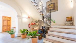 Eine Treppe mit schmiedeeisernem Geländer, einer Holztür und Kübelpflanzen.