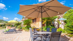 A patio area with a table and chairs, a large umbrella, and a bowl of fruit. - SON GARRETA - Beautiful country house with private pool and free wifi (Campanet)