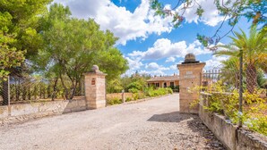 A gravel driveway leading to a stone gate with the inscription "SON GARBEA" and a building with a tiled roof in the background. - SON GARRETA - Beautiful country house with private pool and free wifi (Campanet)