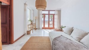 A spacious living room with a large sofa, a wooden coffee table, and a hanging light fixture. - VILLA PORT VERD - Luxury sea-front villa in Cala Bona (Son Servera)