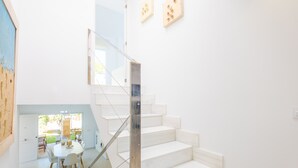 Un intérieur moderne avec un escalier, un coin repas et des œuvres d’art accrochées aux murs.