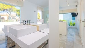 Une salle de bain moderne avec un grand miroir, deux lavabos et une douche à l’italienne.
