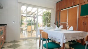 Un comedor con una mesa dispuesta para dos personas, armarios de madera y vistas del patio exterior.