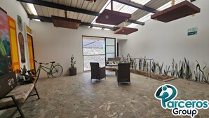 A spacious room with a stone floor, a green bicycle, a sofa, and a potted plant. - PARCEROS GROUP-VACATION ROOM FOR COUPLES, FLOOR 1, PEREIRA (pereira)