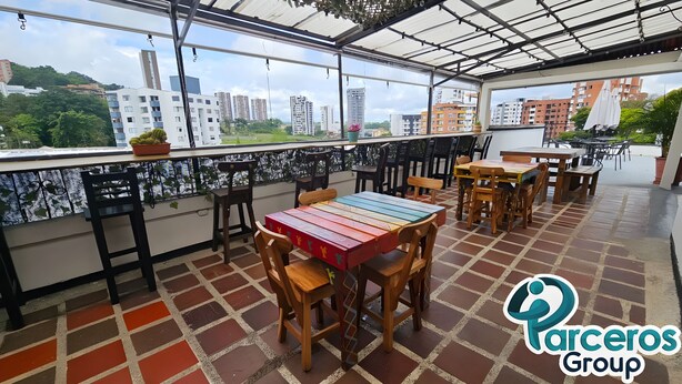 A rooftop terrace with outdoor seating, a view of the city, and a sign for 'Parceros Group'. - PARCEROS GROUP-VACATION ROOM FOR COUPLES, FLOOR 1, PEREIRA (pereira)