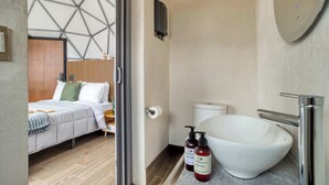 A modern hotel room with a large bed, a white sink, and a toilet. - Umbral | Sky Domes in Roma Norte (Tonali) (Ciudad de México)