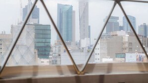 A room with a geometric window design, a view of a cityscape with various buildings, and a wooden floor. - Umbral | Sky Domes in Roma Norte (Tonali) (Ciudad de México)