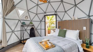 A modern bedroom with a geometric ceiling, a bed with a tray of breakfast, and a view through an open door. - Umbral | Sky Domes in Roma Norte (Tonali) (Ciudad de México)