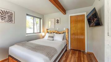 Une chambre à coucher avec une tête de lit en bois, une grande fenêtre et une porte.