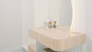 Un baño moderno con tocador de madera, un espejo grande y un taburete redondo.