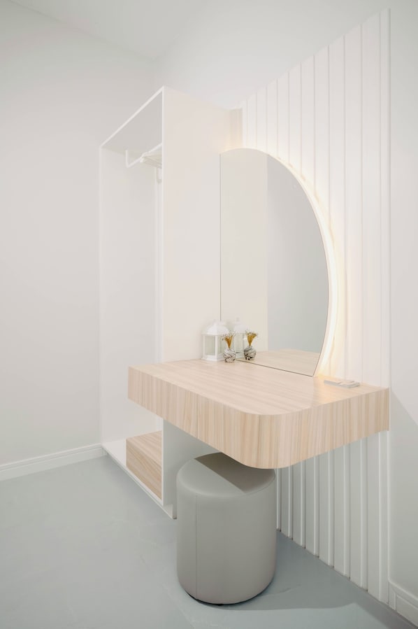 A modern bathroom with a wooden vanity, a large mirror, and a round stool.