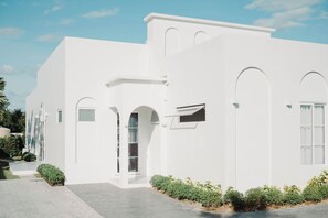 Un edificio moderno blanco con ventanas arqueadas y techo plano.