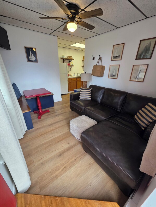 Una sala de estar con un sofá de cuero, una mesa roja y un ventilador de techo.
