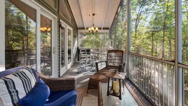 A covered porch with a ceiling fan, wicker furniture, and a view of the forest. - Cozy cabin w/ Screened porch & BBQ (Hedgesville)